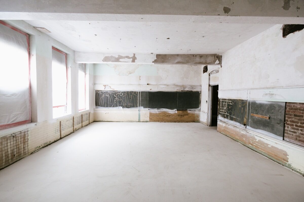 An empty room mid-renovation with exposed walls and windows