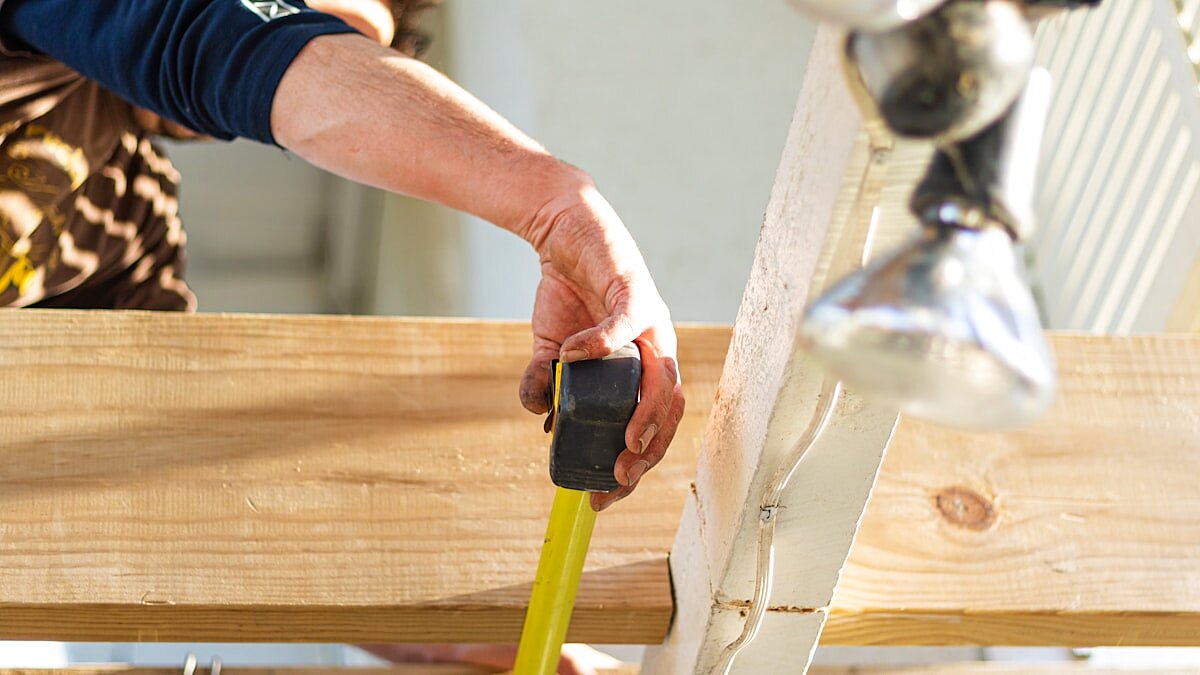 Builder measuring room dimensions with a tape measure on a construction project