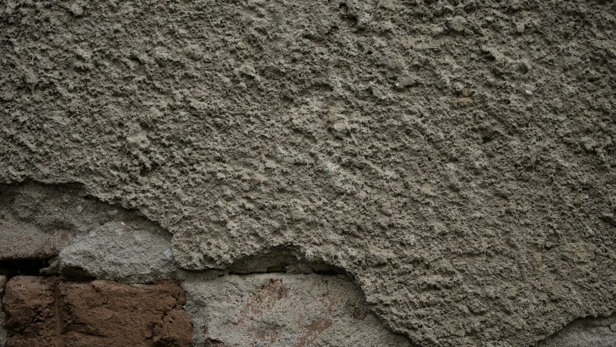 Rough textured lime-rendered wall above exposed brickwork on an older building